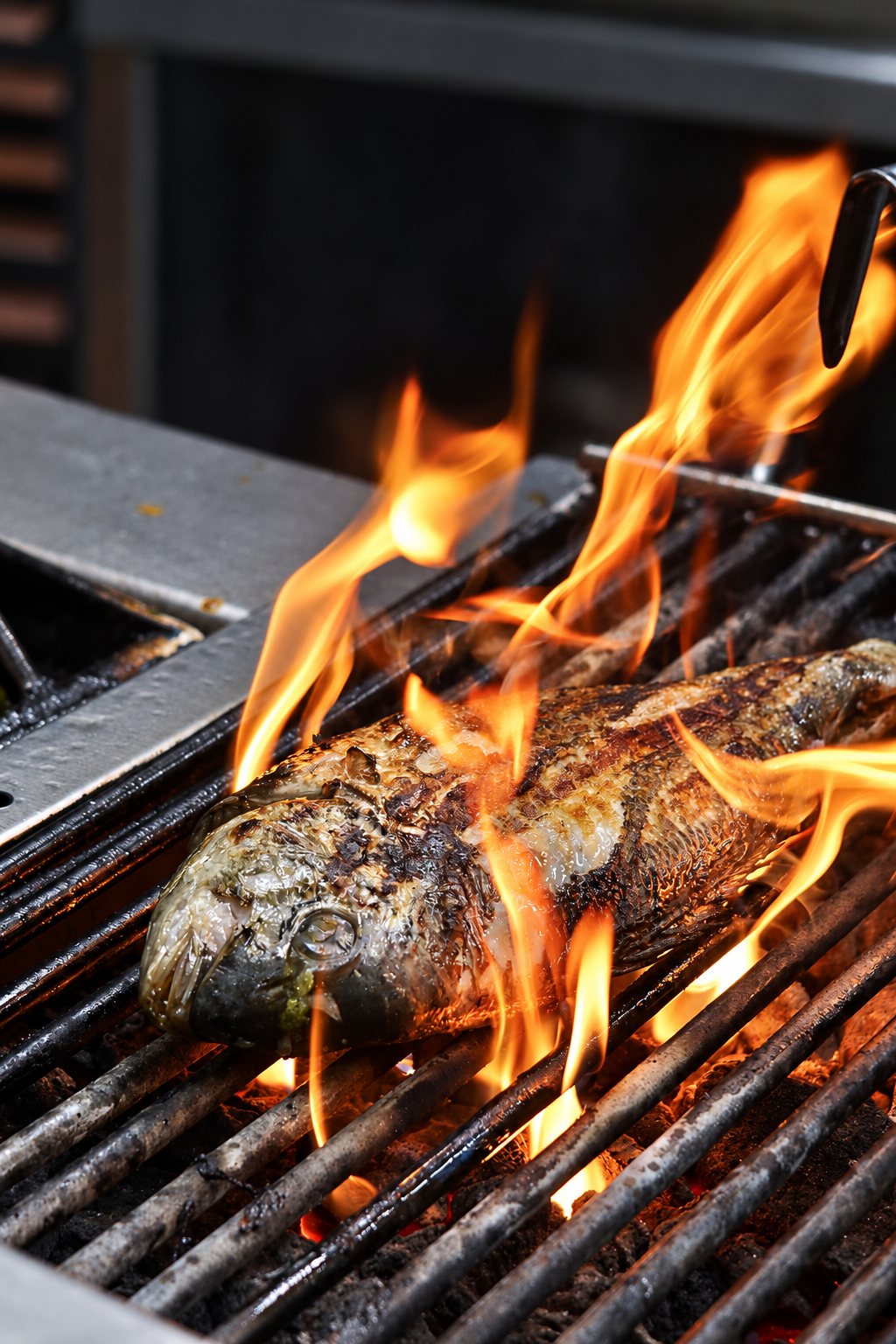 Un poisson entier cuit sur une grille de barbecue en métal, entouré de flammes orange vives dans une cuisine de restaurant.