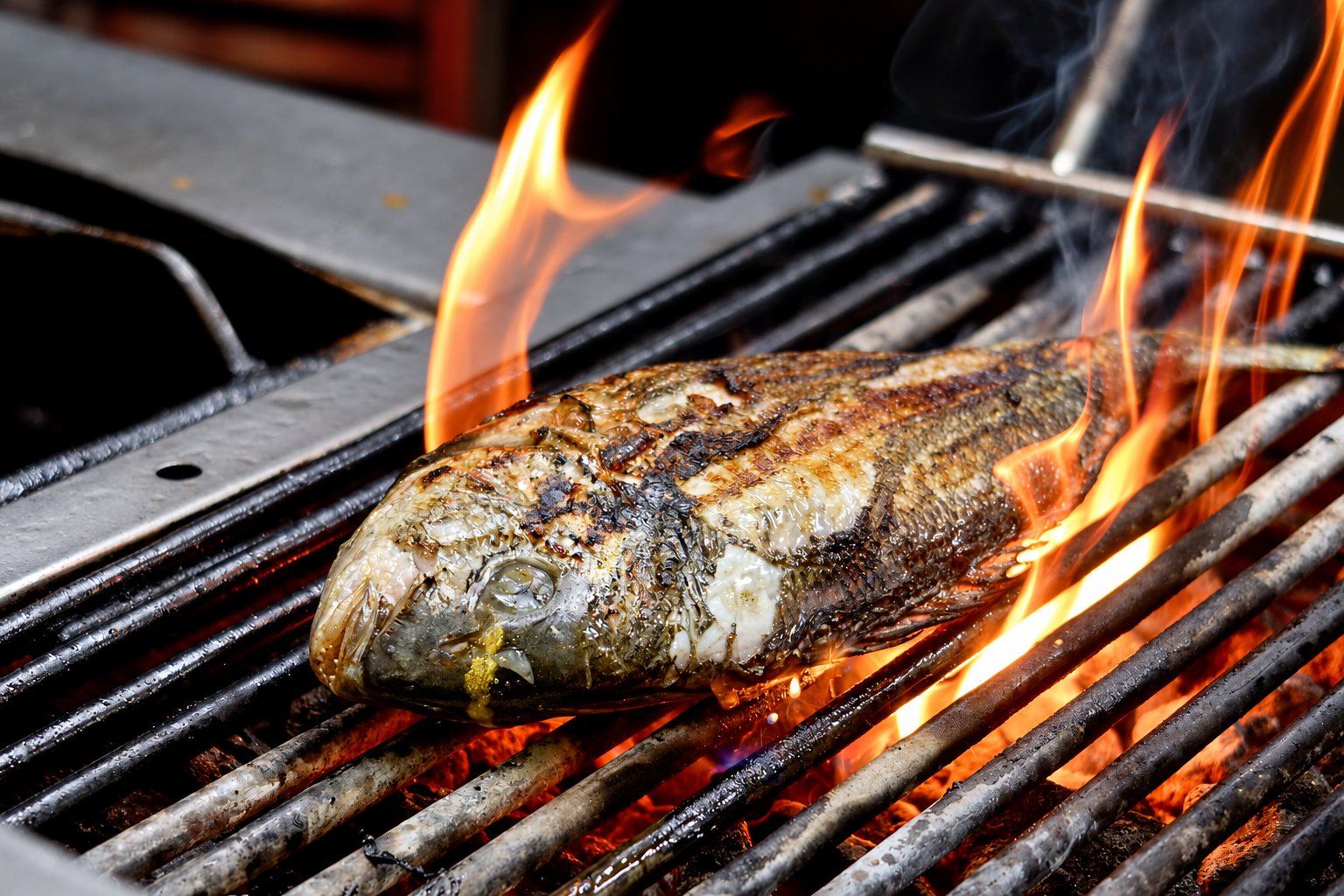 Un poisson entier cuit sur une grille métallique au-dessus des braises, entouré de grandes flammes orange.